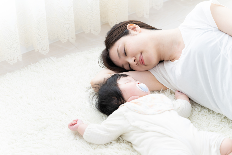 子どもと一緒に寝ている母親のイメージ