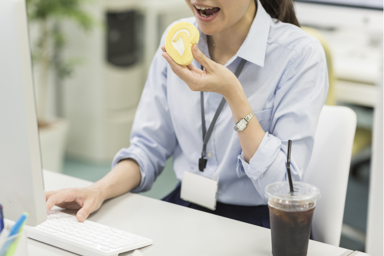 勤務中に甘いものを食べている女性のイメージ