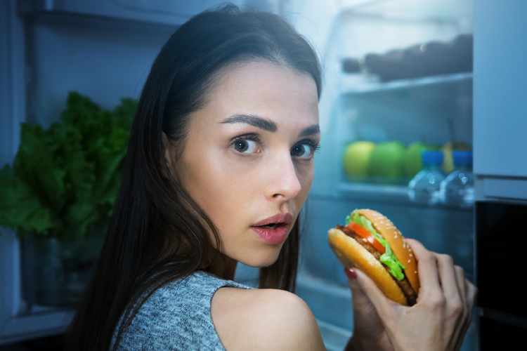 夜食にハンバーガーを食べる女性