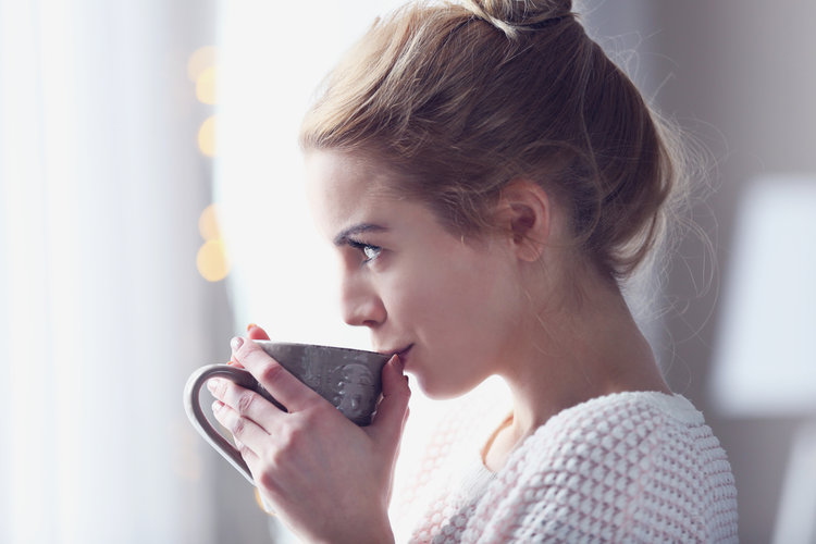 カップで飲み物を飲む女性