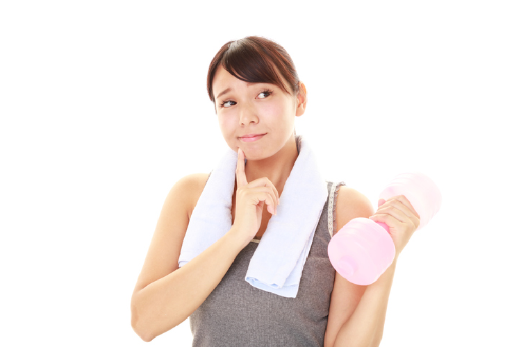 ダンベルを持って小首を傾げる女性