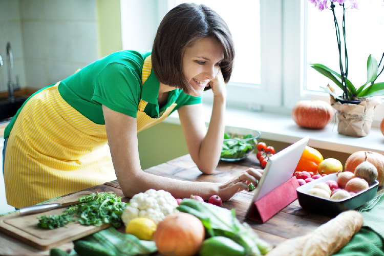 料理をしながらパソコンをいじる女性