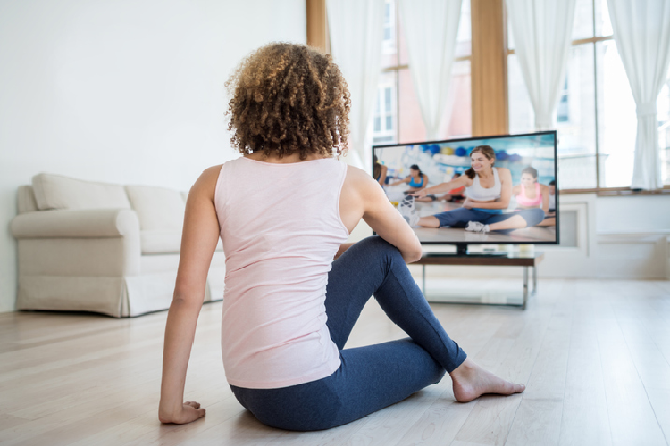 テレビを見ながらストレッチする女性