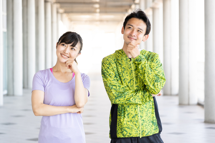 スポーツウェアを着た男女が首を傾げている