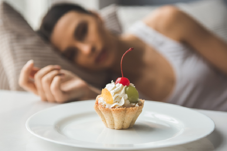 ケーキを前にして悲しそうに寝転ぶ女性