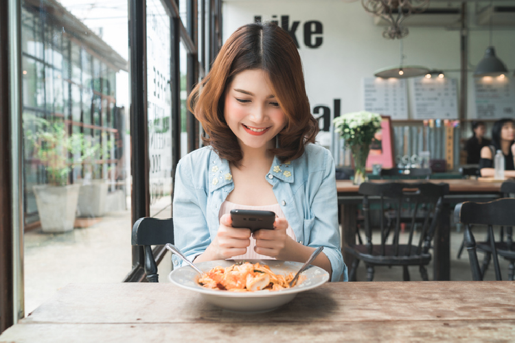 カフェで料理の写真を撮る女性