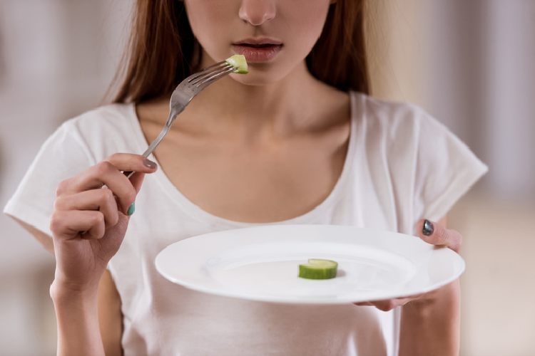 小さなズッキーニを口へ運ぶ女性