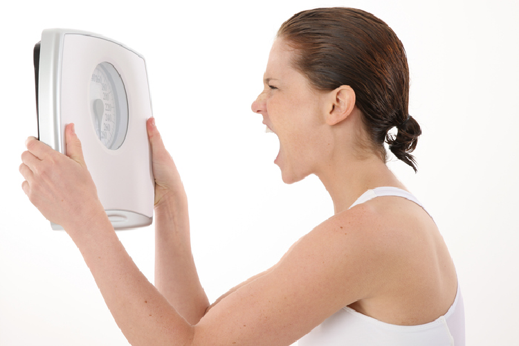 体重計に向かって叫ぶ女性
