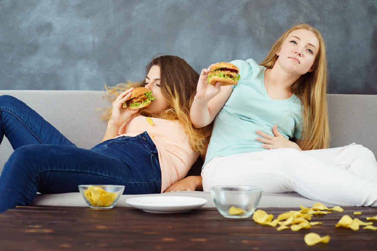 ハンバーガーを持って苦しそうにする女性
