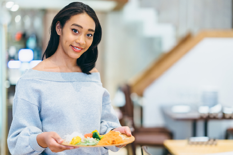 料理の乗ったお皿を持って微笑む女性