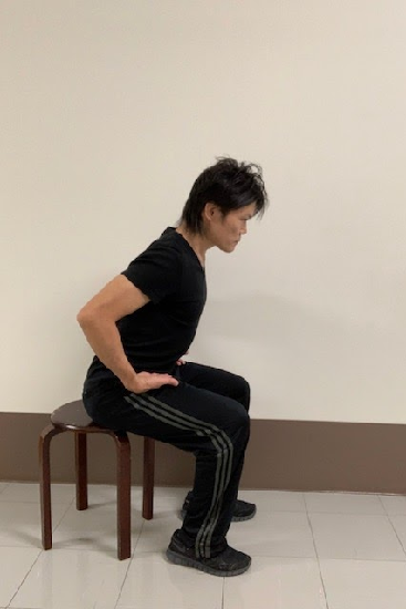 椅子をつかってスクワットする男性