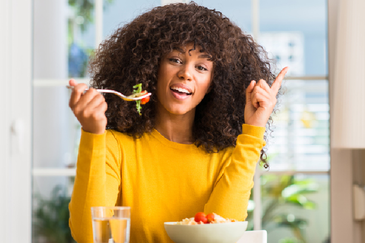 食事をしながら人差し指でポーズをとる女性