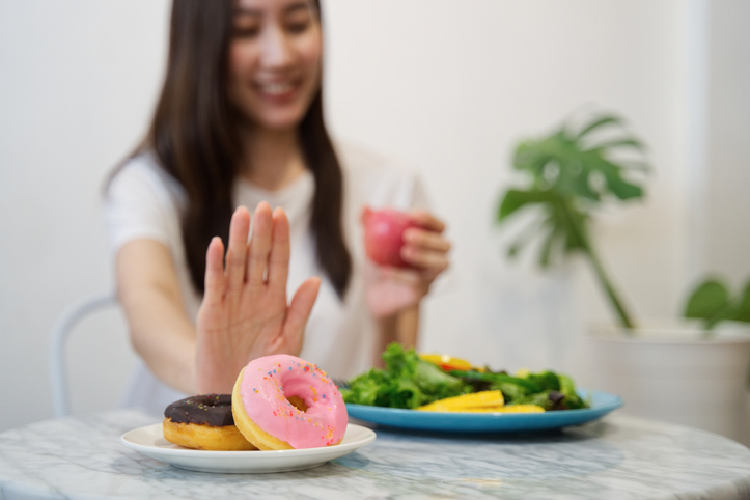 ドーナツを拒否してサラダを食べる女性