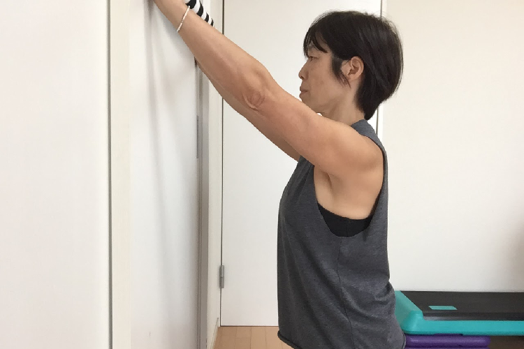 タオルを壁に当てる女性