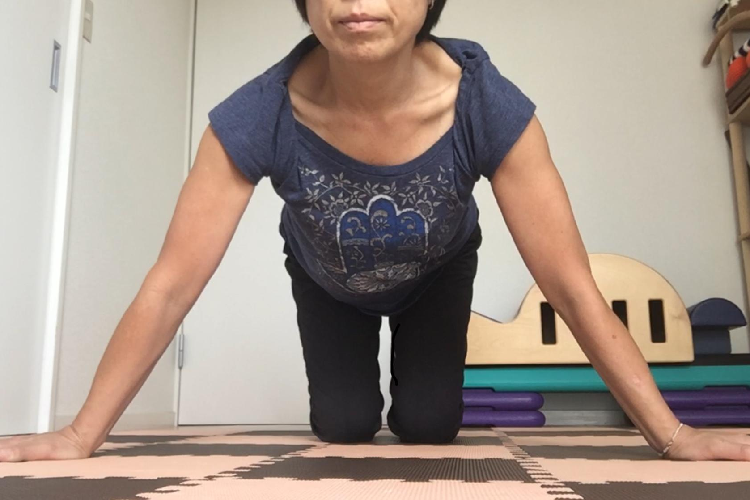 両手を床につく女性