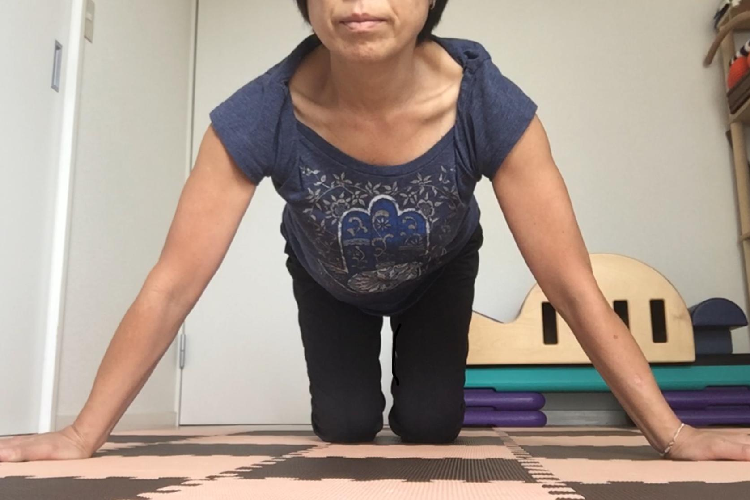 両手を床につく女性