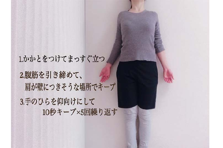壁に背をちつけ姿勢を正す女性