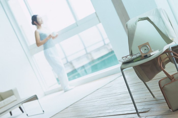 カーテンを開けて朝日を浴びている女性のイメージ