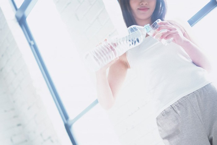 朝起きて水を1杯飲んでいる女性のイメージ