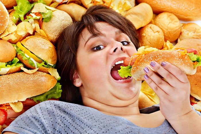 お腹いっぱいでも残さず食べている女性のイメージ